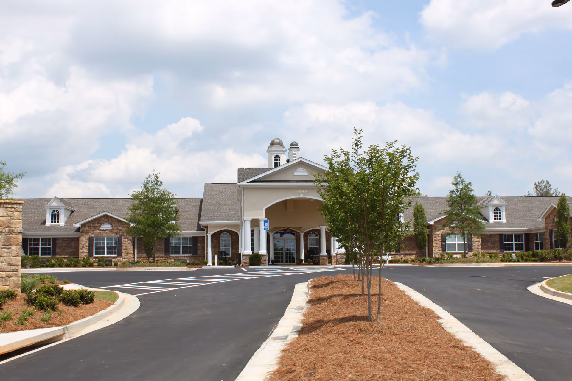 Front exterior view of Benton House of Newnan, a single-story building with a covered entrance supported by white columns, surrounded by landscaped greenery and a paved driveway.