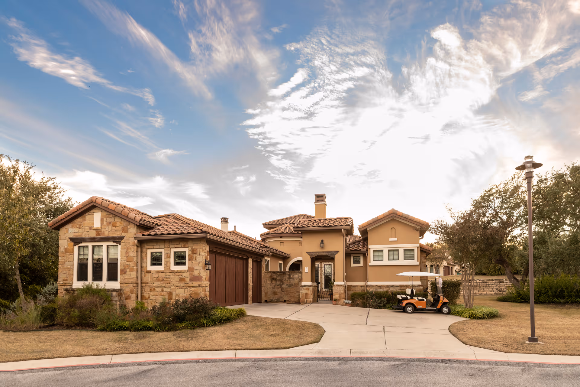 Stone and stucco senior living facility exterior with curved driveway and golf cart