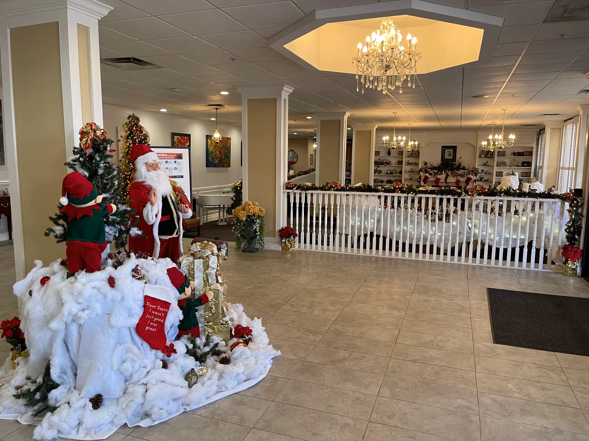 Bright lobby with Christmas decorations, Santa figure, elves, and garlands along the railing.