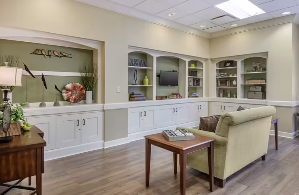 A comfortable senior living lounge with a sofa, coffee table, and built-in shelving.