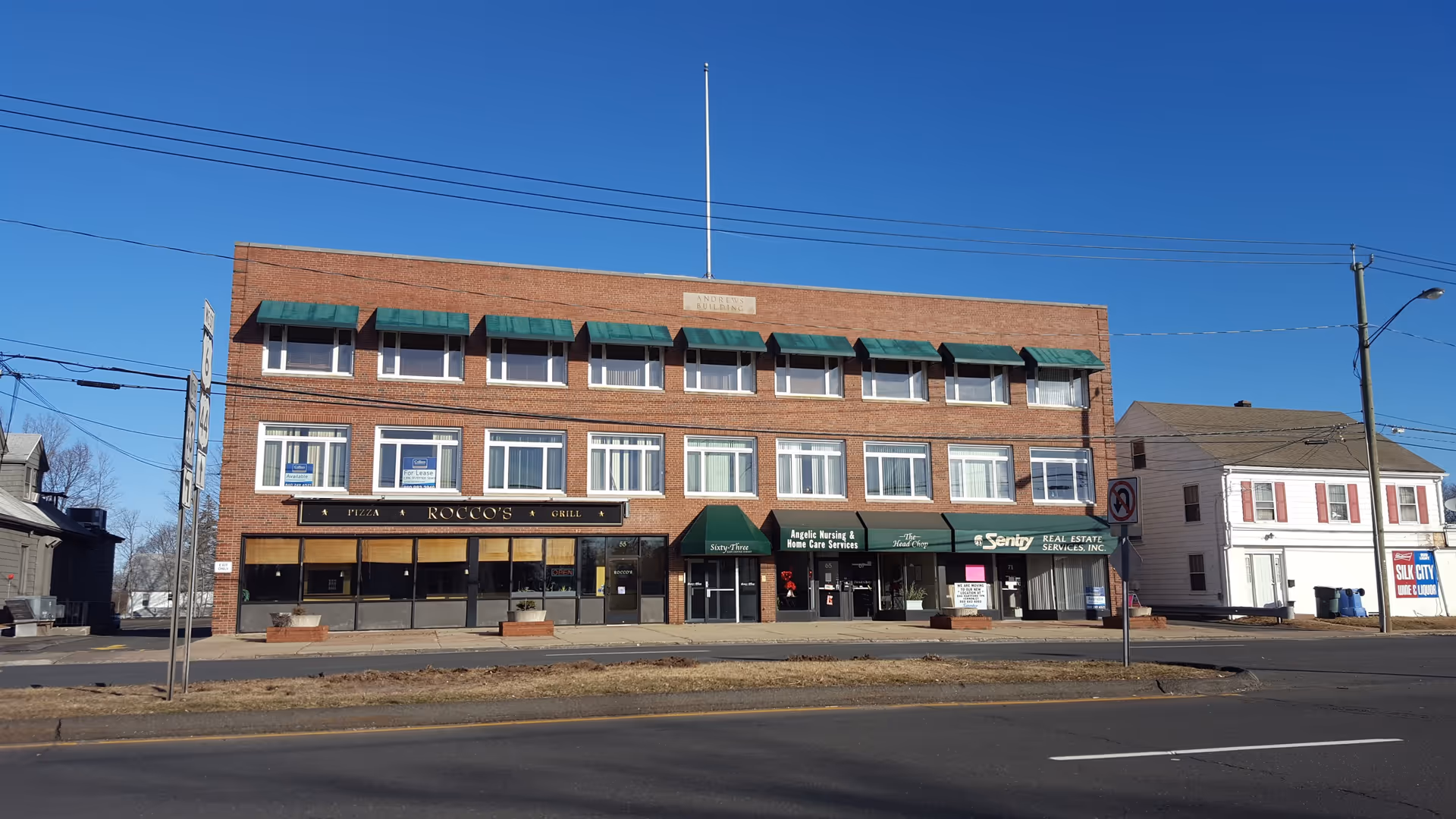 Brick building with multiple storefronts, including Angelic Home Care Services, Inc., on the street.