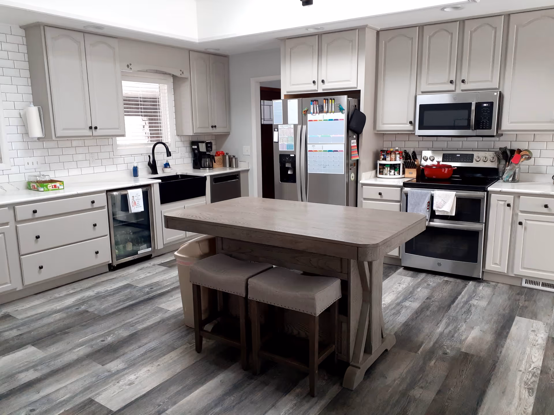 Modern kitchen with white cabinets, stainless steel appliances, and an island in a senior living facility.