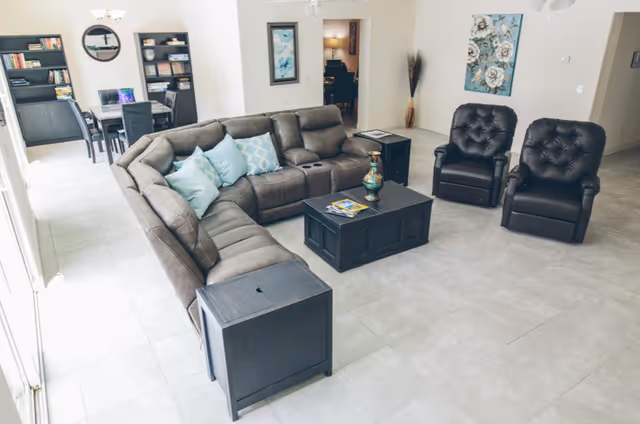 Spacious modern living room lounge with sectional sofa, teal cushions, and black armchairs.