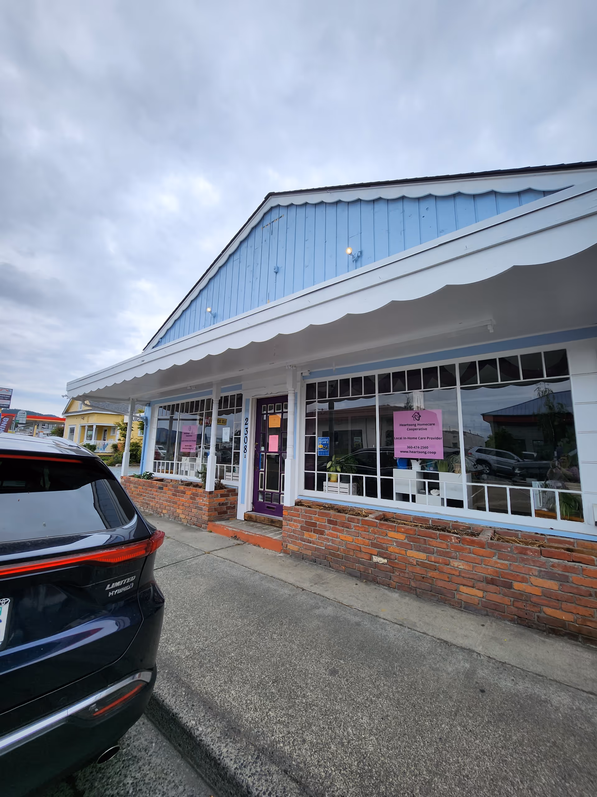 Front exterior of Heartsong Homecare Co-op with blue awning and brick base.