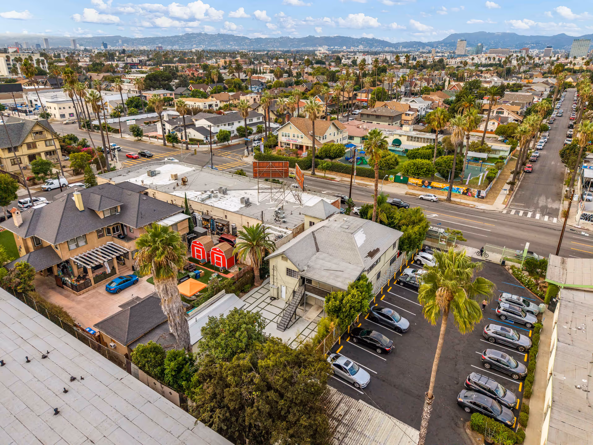 Aerial view of a dense residential neighborhood with rooftops, streets, and palm trees.