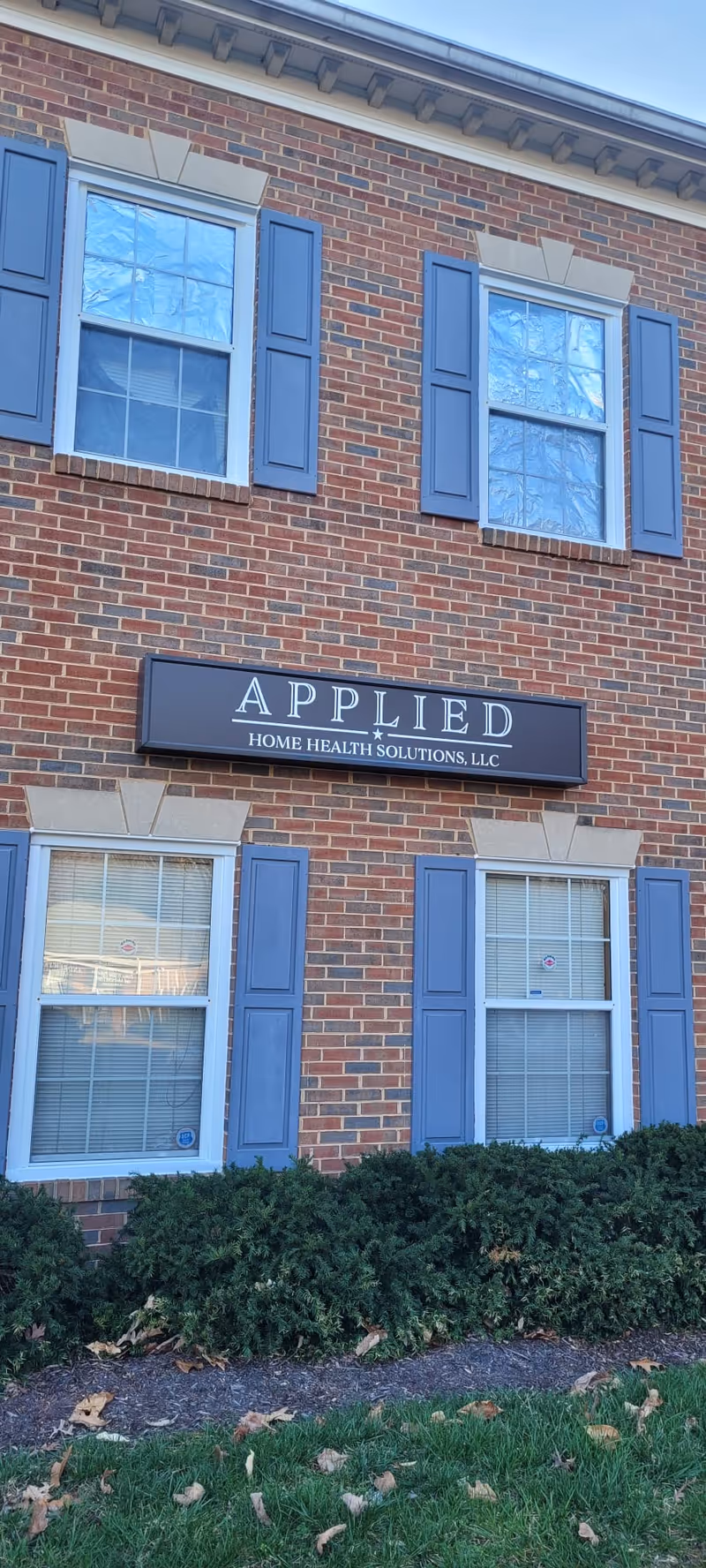 Brick building exterior with blue shutters and a sign for Applied Health Solutions LLC.