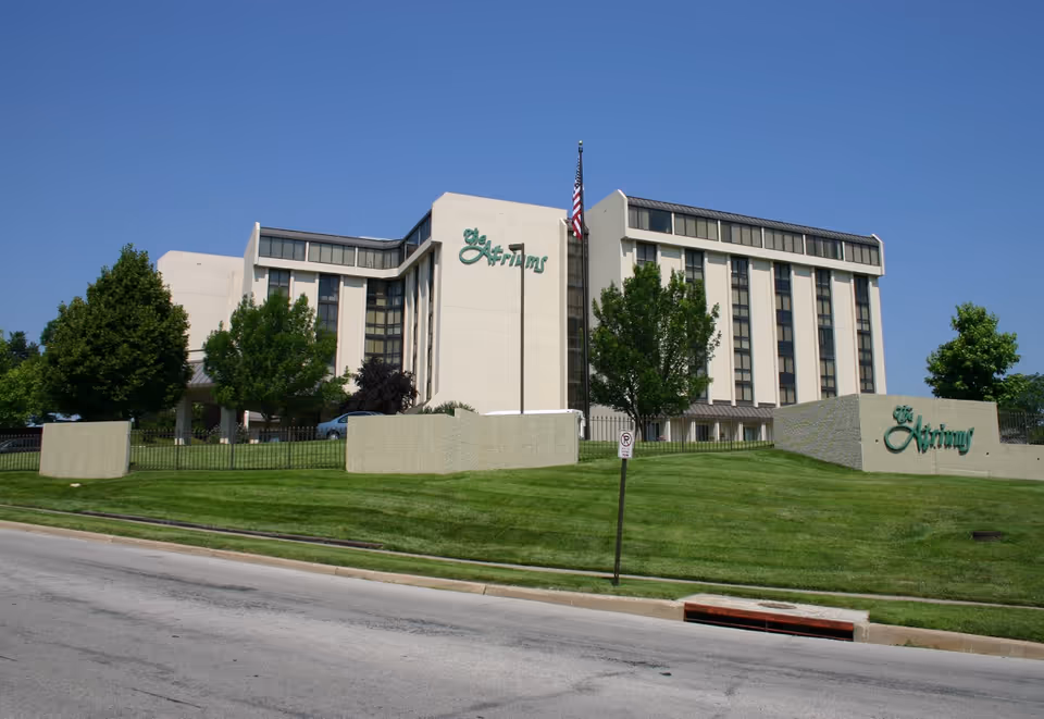 Exterior view of The Atriums Senior Living Community building with green lawn and signage.