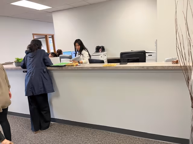 Reception area with staff assisting residents at a long counter inside a senior facility.