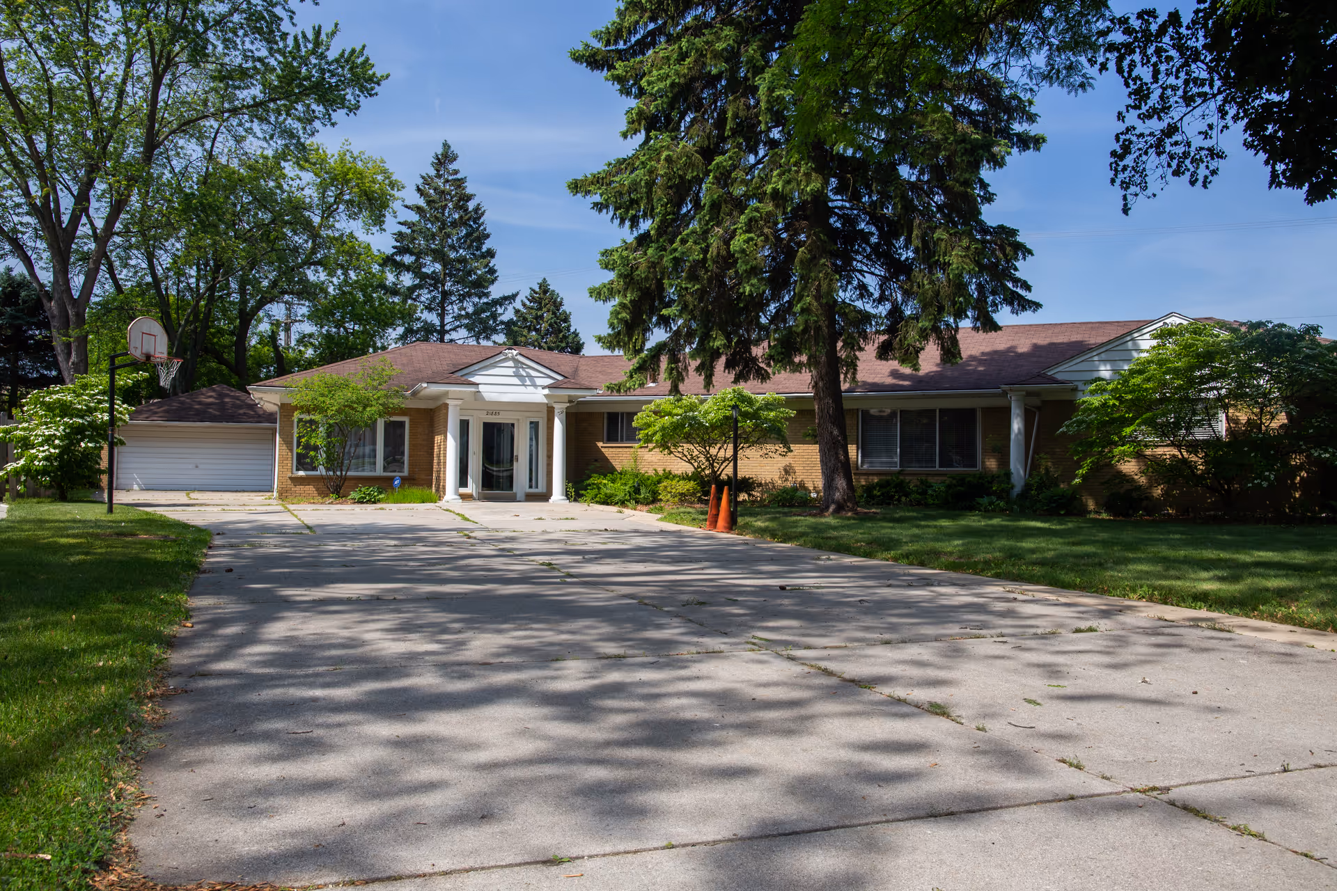Single-story brick facility with front entrance, driveway, and surrounding trees.