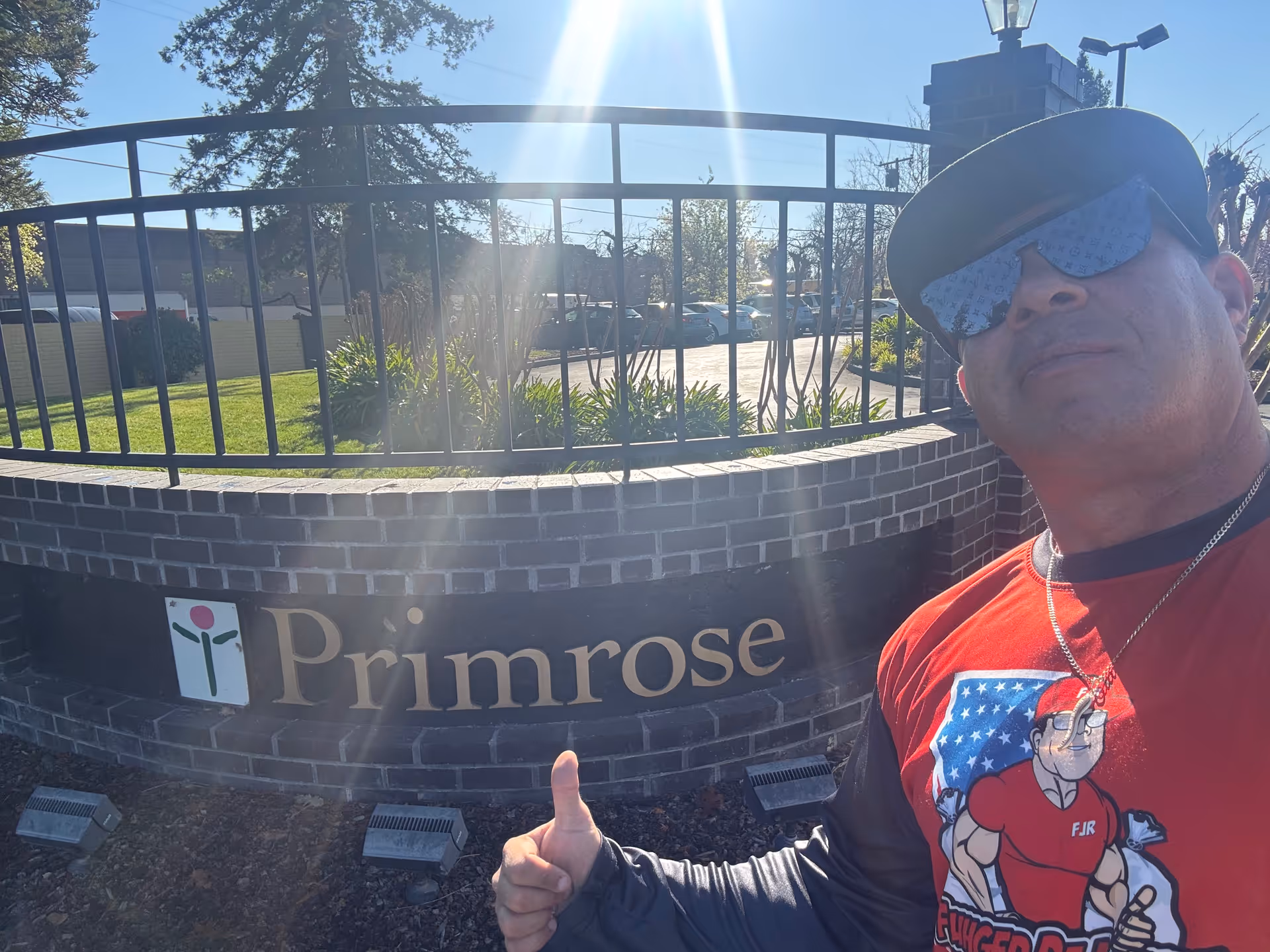 Selfie of a man in front of a brick Primrose sign at the entrance.