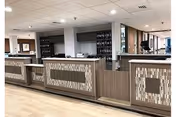 Bright interior lobby with a long front desk and decorative panels.