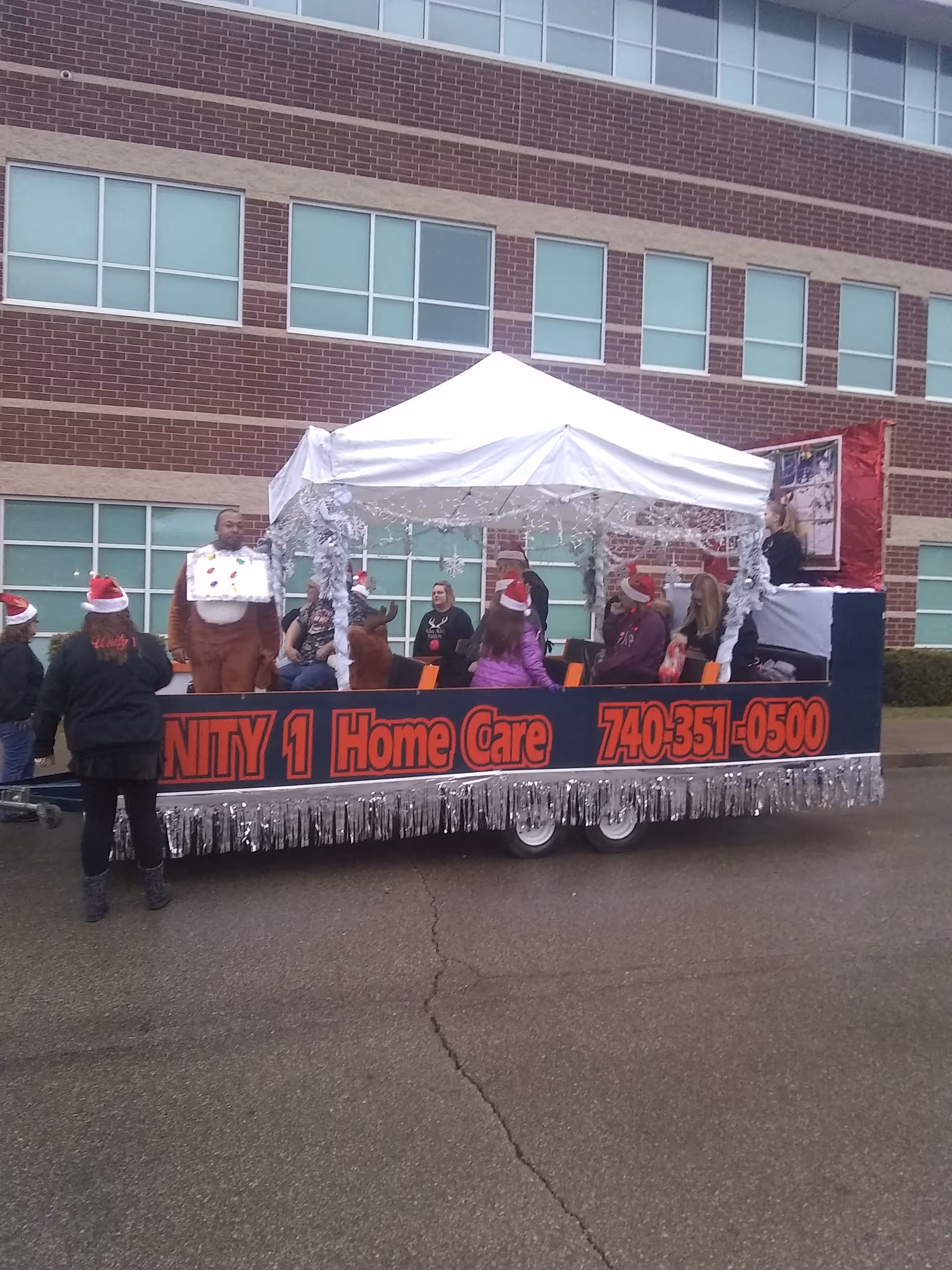 Outdoor parade float labeled Unity 1 Home Care with people under a white canopy.