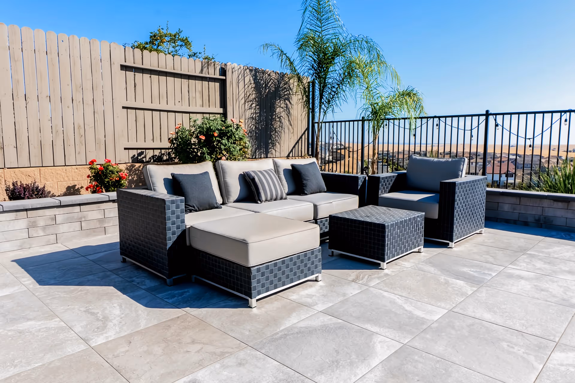 Outdoor patio at Grand Dignity Homes with wicker furniture, planters, and a distant view.