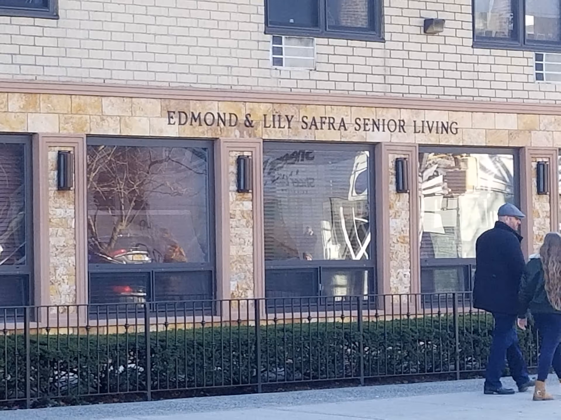 Front view of Edmond & Lily Safra Senior Living exterior with pedestrians walking.