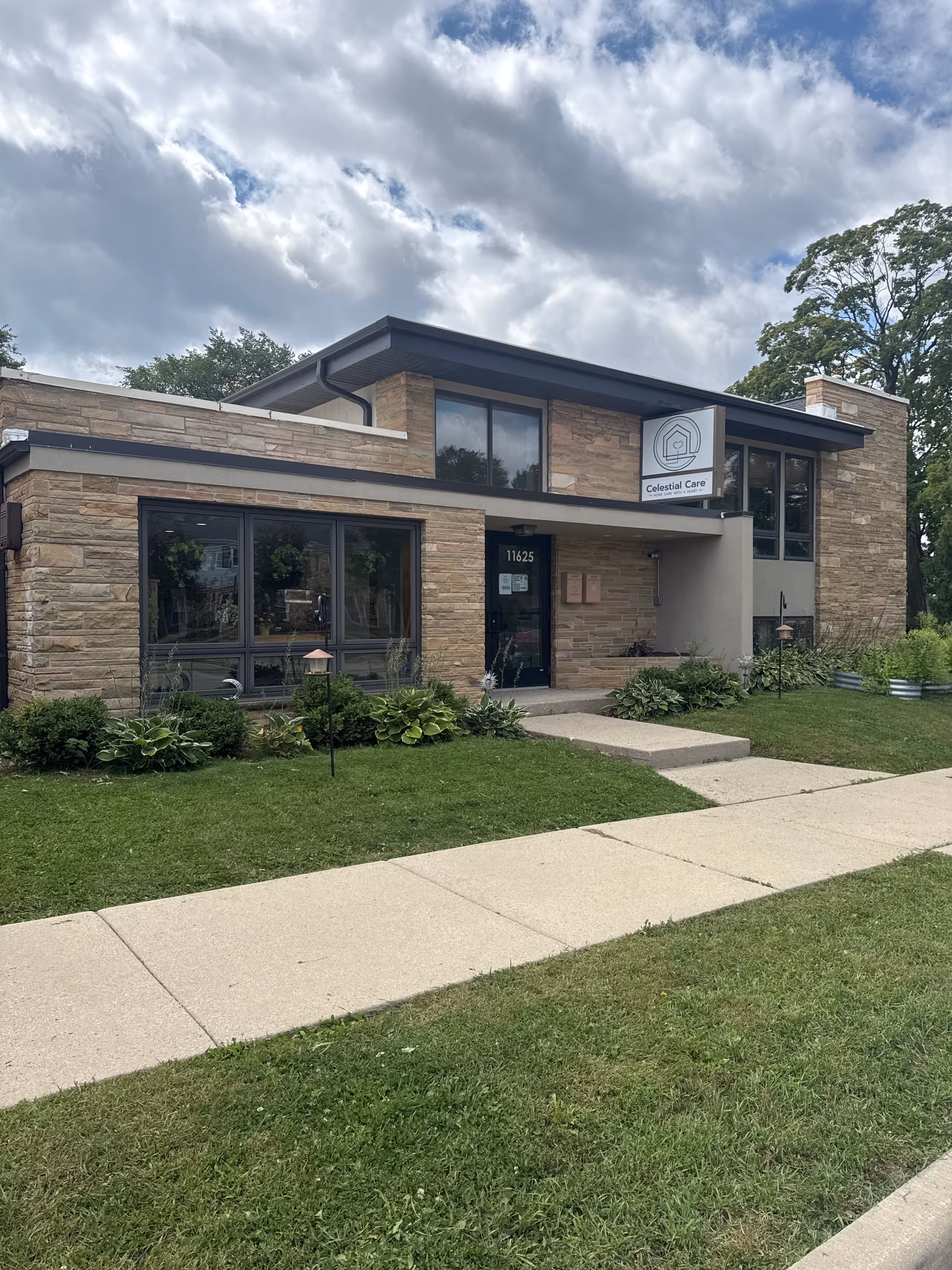 Celestial Care building exterior with stone facade and large windows on a sunny day.