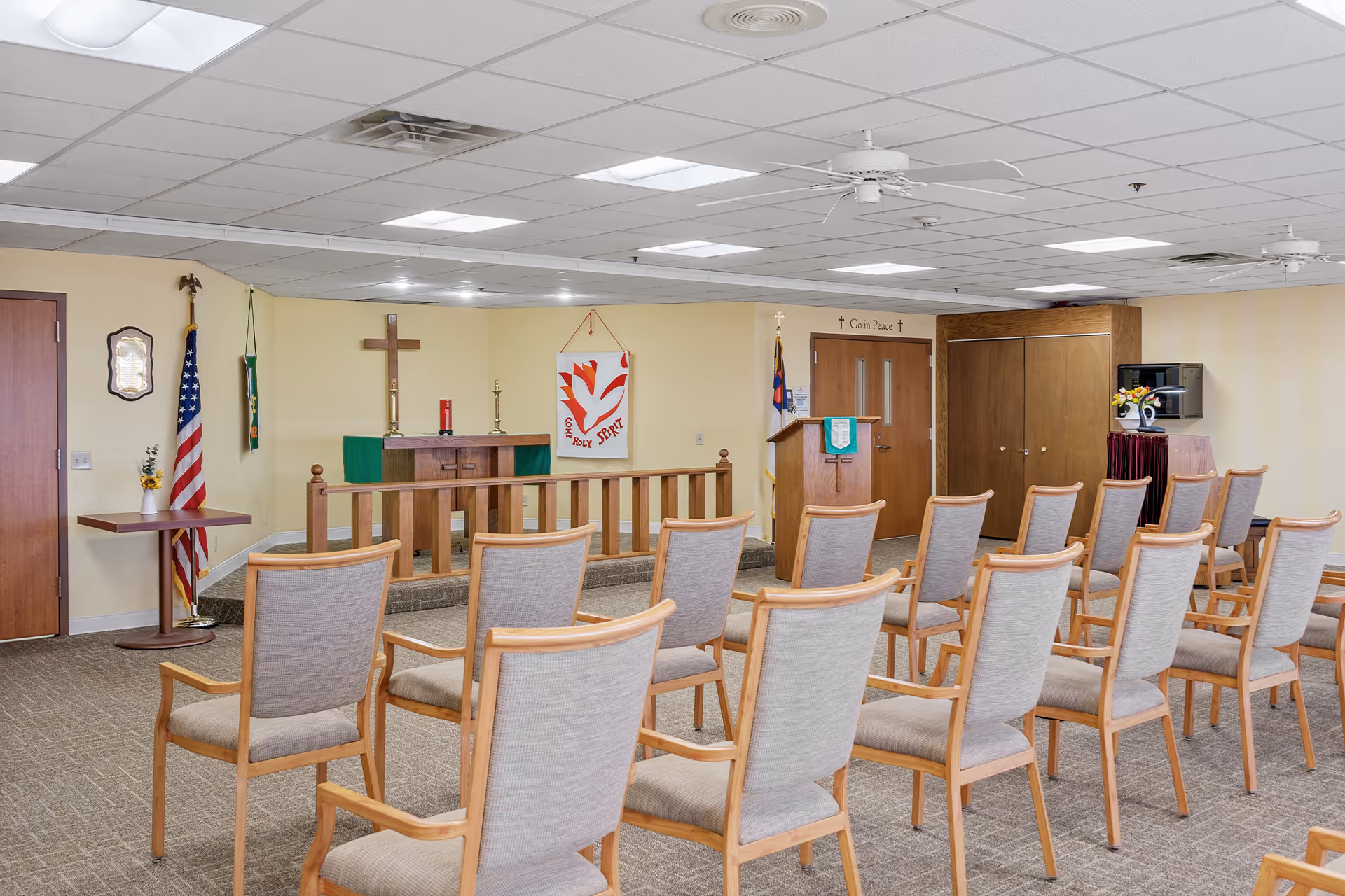 Chapel-style interior with seating, altar, cross, and flags.