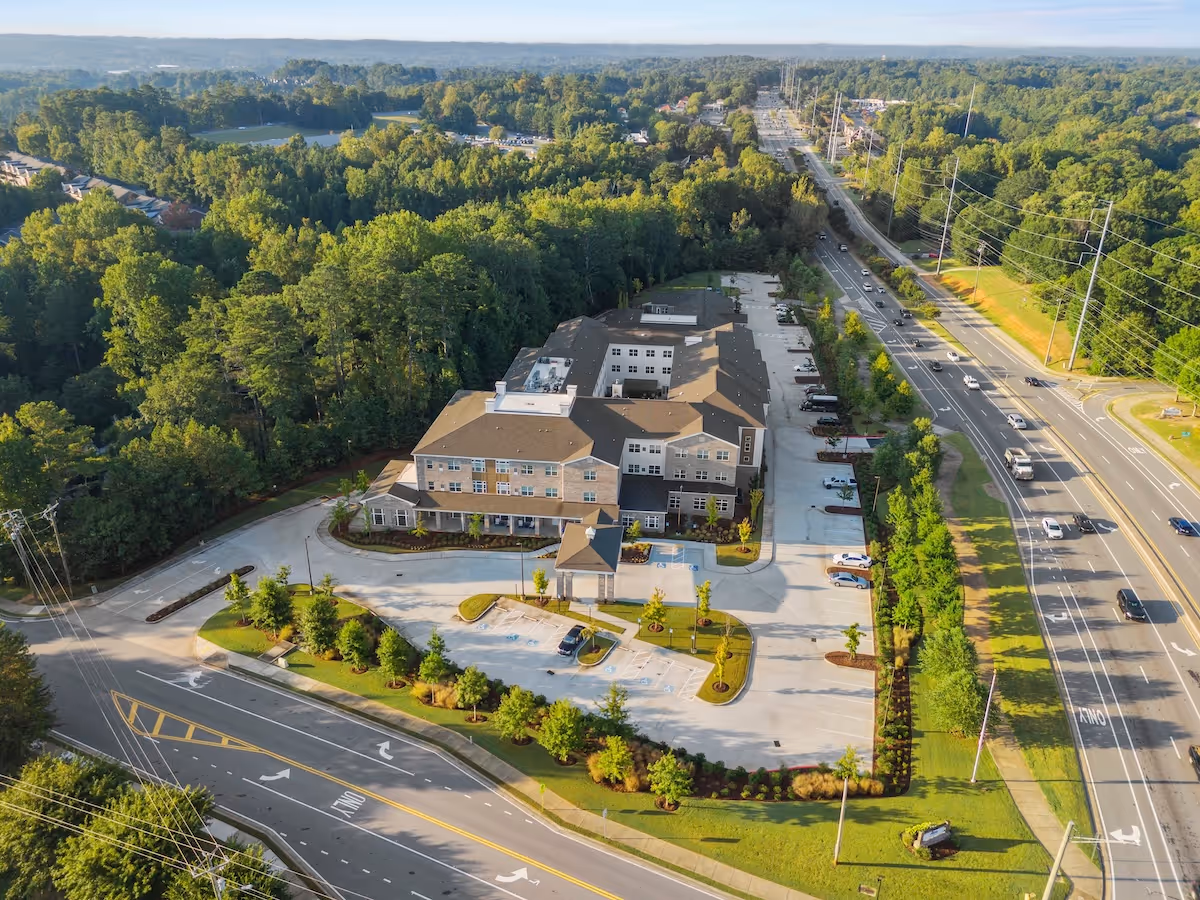 Aerial view of Alto Johns Creek senior living facility with parking and surrounding trees.