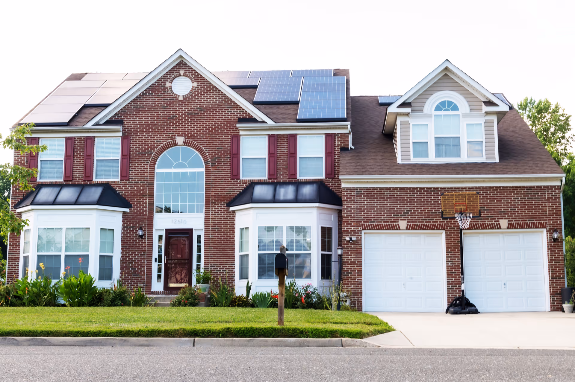 Brick two-story assisted living facility with solar panels, arched window, and double garage.
