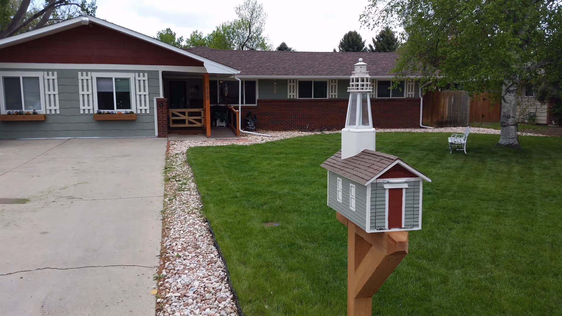 Front exterior view of a single-story senior living home with green lawn and a decorative mailbox.