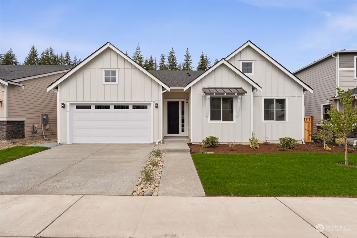 Front view of a modern two-car garage home with manicured lawn and walkway.