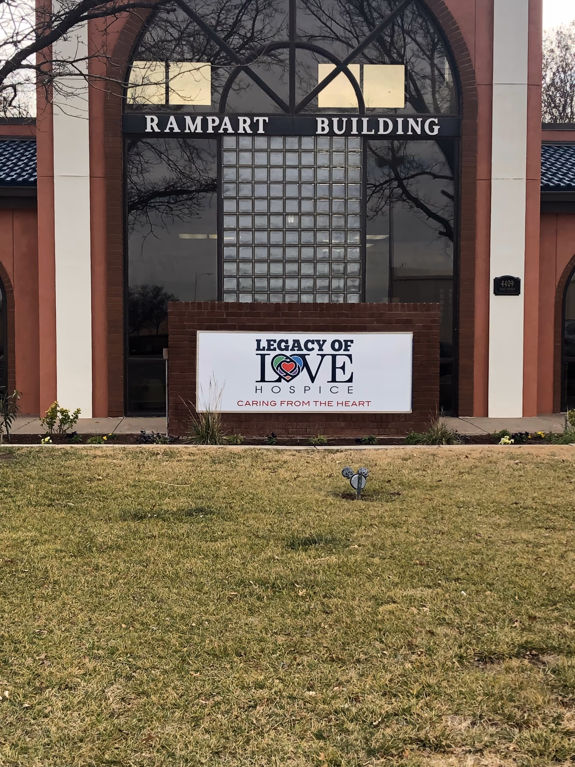 Front view of Legacy of Love Hospice building with sign and grassy lawn