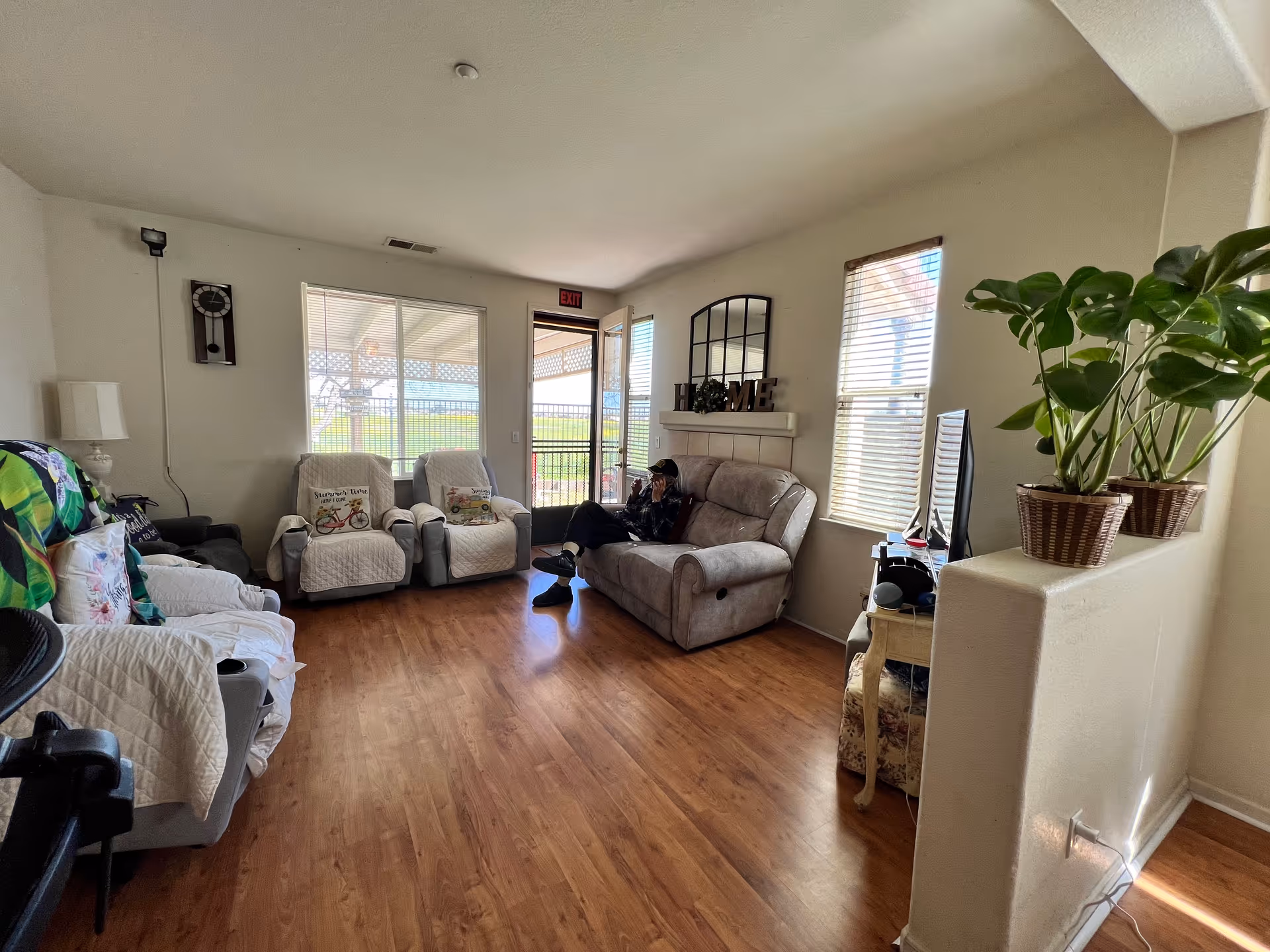 Cozy living room in a care home with recliners, sofa, TV, and a resident resting.