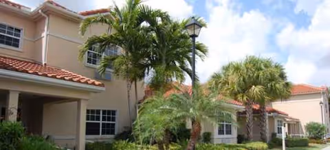 Exterior view of Sonata Delray Beach building with palm trees and a lamp post.