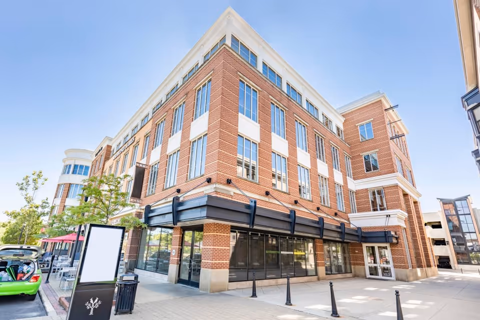 Exterior view of a brick senior living building with large windows and storefront along the street.