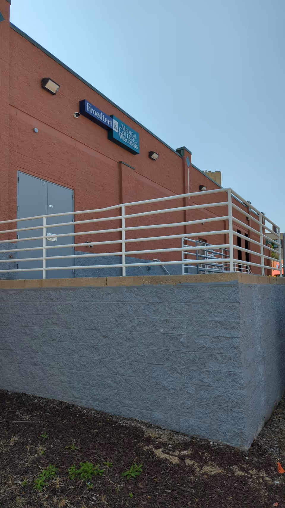 Red brick facility exterior with white railing, ramp, and doors.