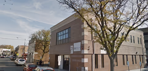 Exterior view of a brick two-story medical facility on a tree-lined street.