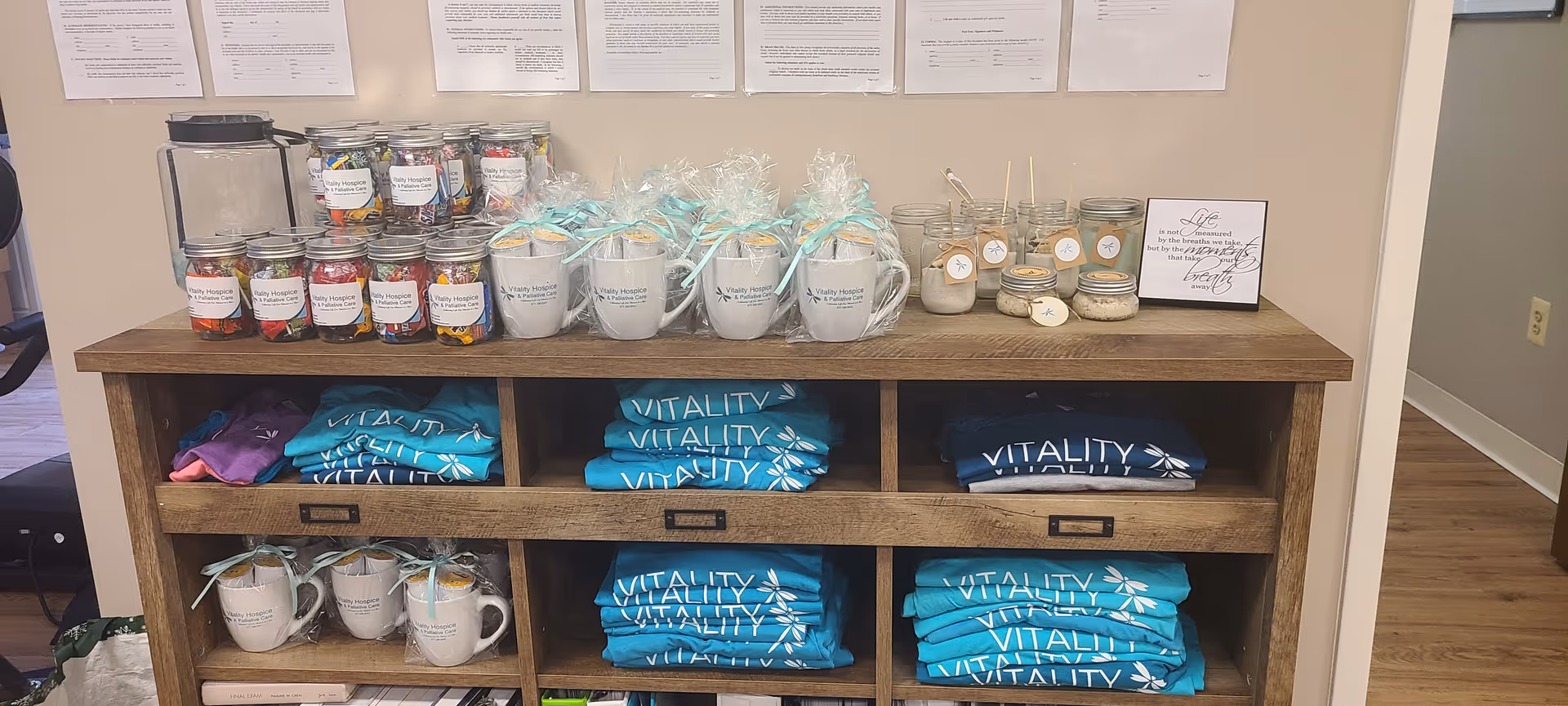 A wooden cubby shelf displays turquoise Vitality apparel, mugs, and jars.