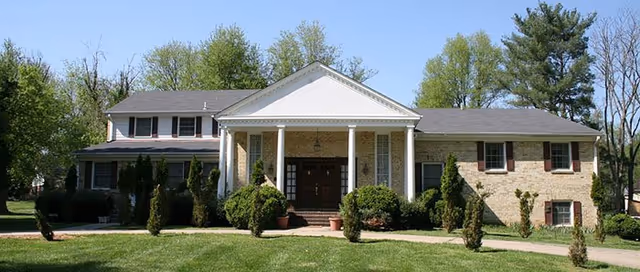 Front exterior of Potomac Seniors Village, a brick building with white columns and a green lawn.