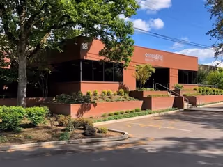 Exterior view of Emerging Health brick facility with trees and landscaped planters.