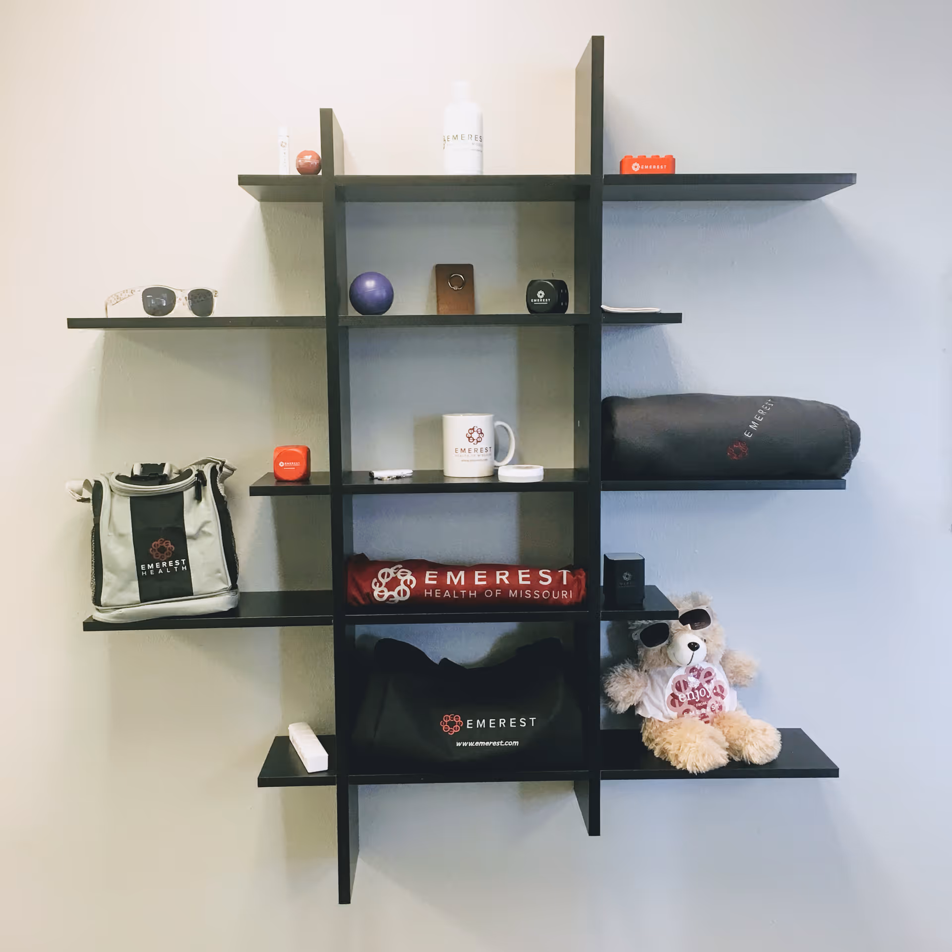 A black wall shelf displays Emerest Health merchandise against a gray wall.