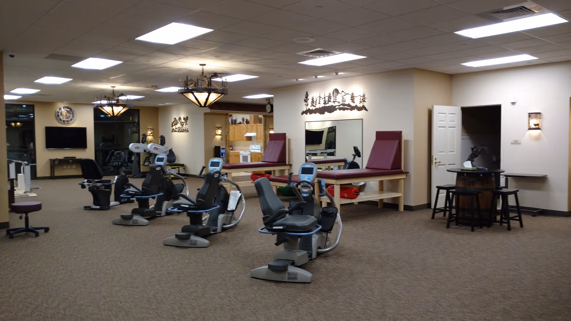 Senior living facility fitness center with exercise bikes and seating areas.