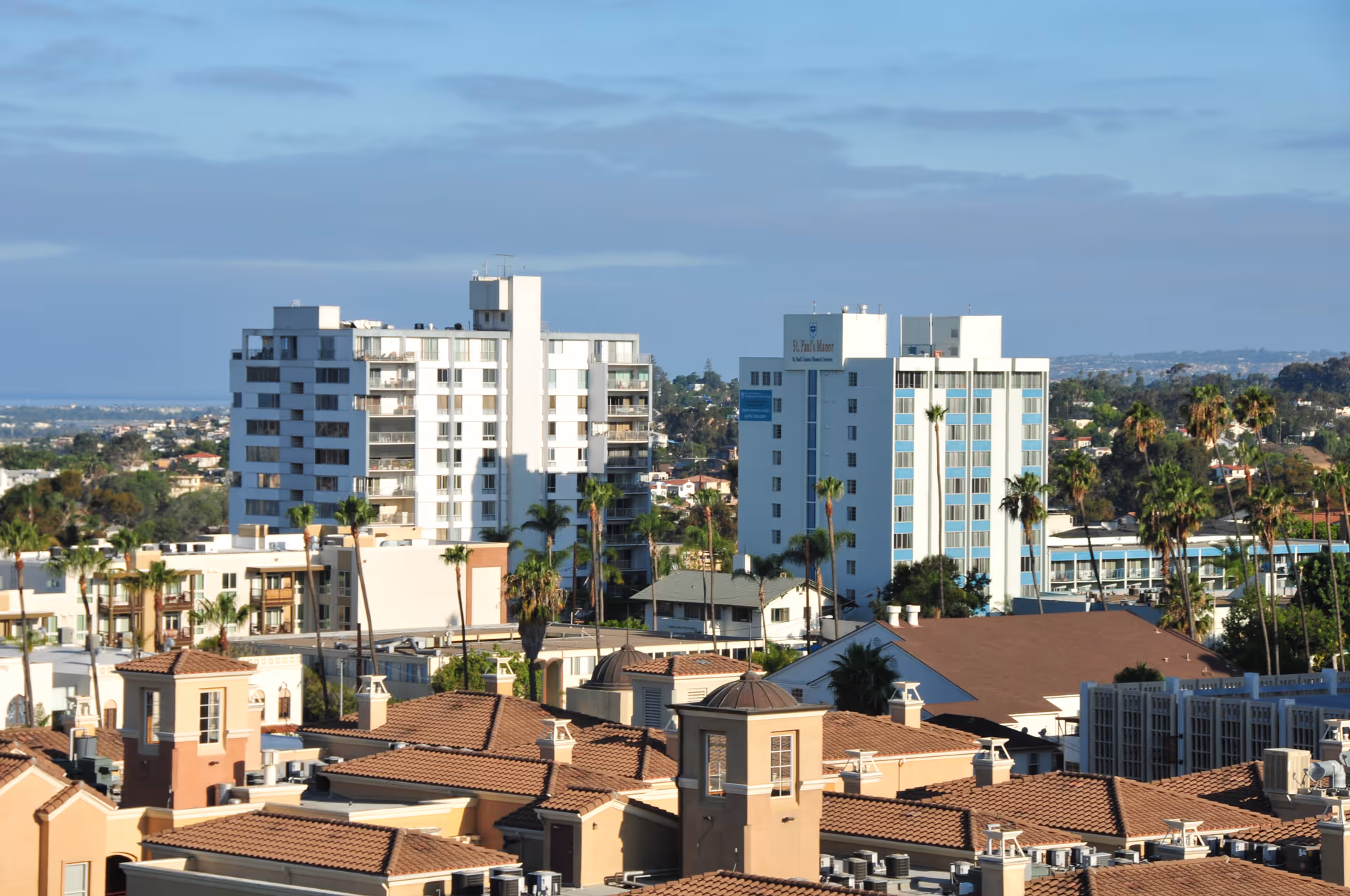 Cityscape view of St. Paul's Manor exterior with surrounding rooftops and palm trees.