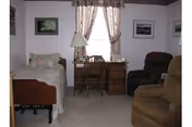 Cozy bedroom with bed, dresser, desk, chair, and window with curtains.