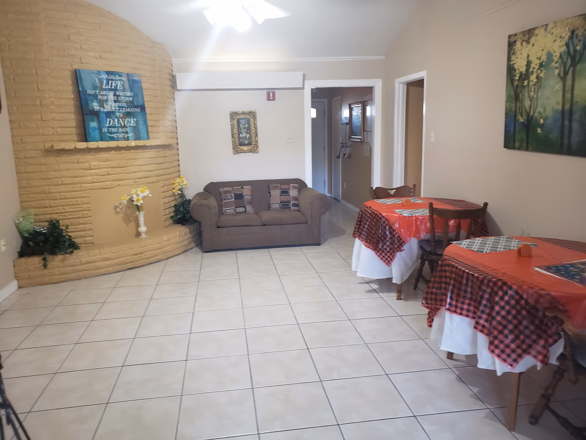 Cozy senior living common area with couch, round table, tiled floor, and wall art.