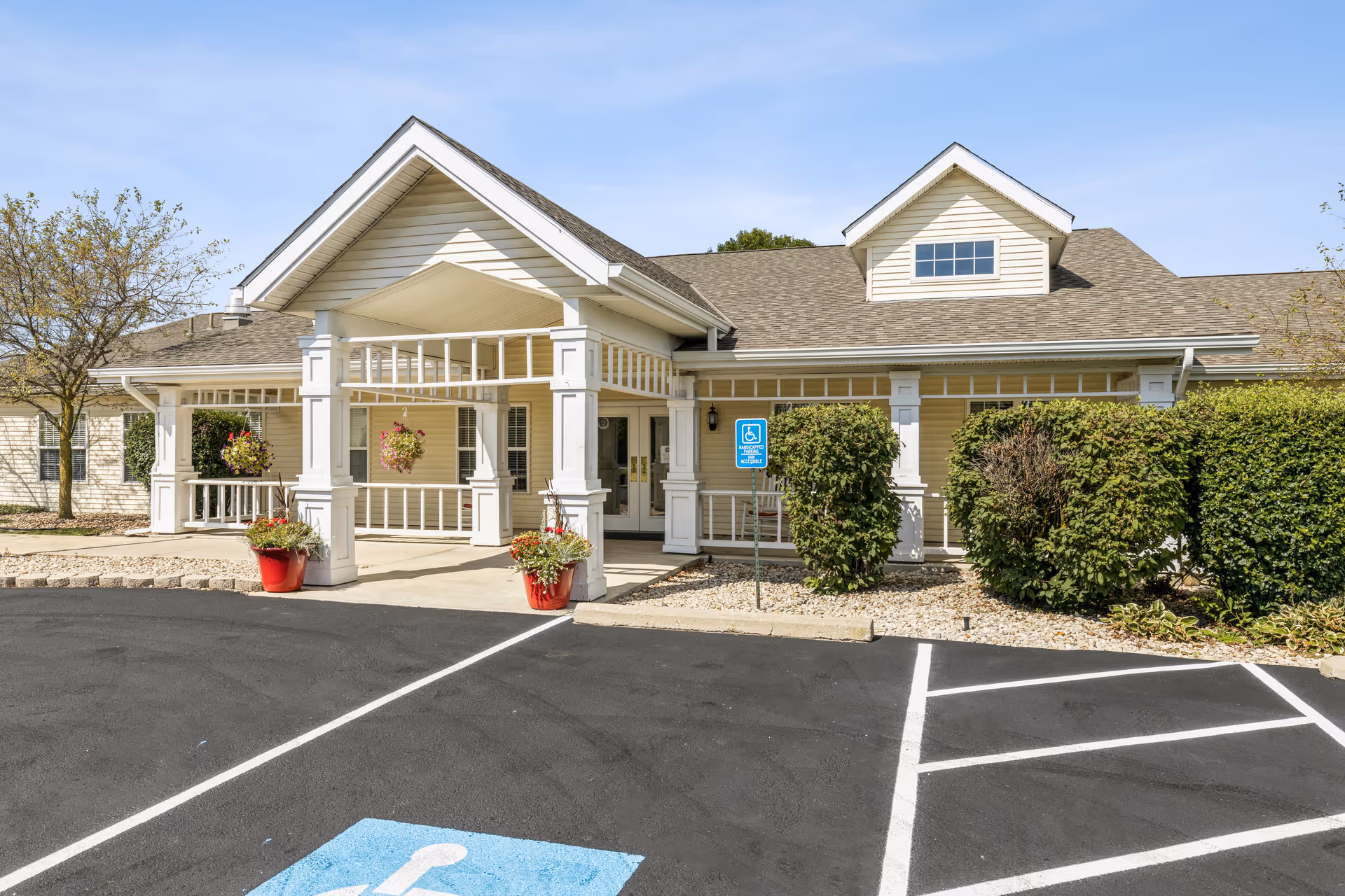 Beige senior living facility front with a welcoming porch and handicap parking.