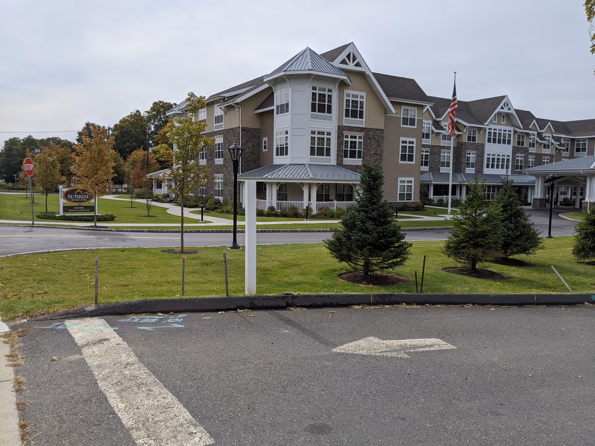 Exterior view of Sunrise of Wilton, a multi-story senior living building with trees and lawn.