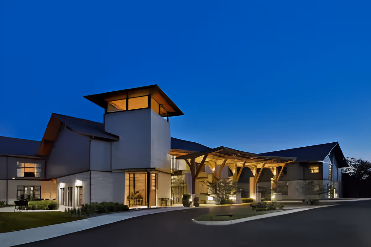 Exterior front entrance of Cumberland Pointe Health Campus at dusk with an illuminated wooden canopy and tower.