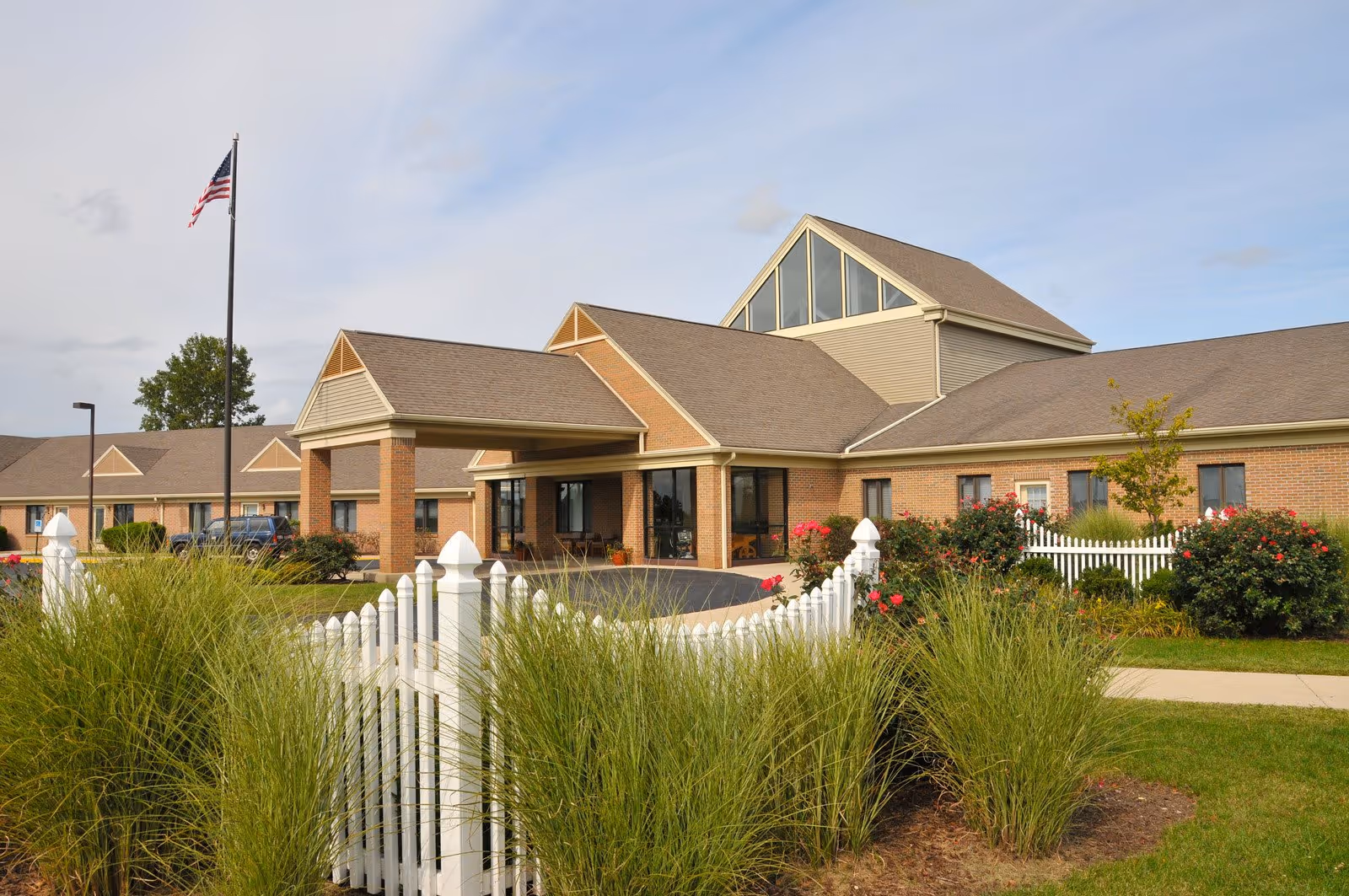Exterior view of Otterbein Pemberville SeniorLife Community with brick building and white fence.