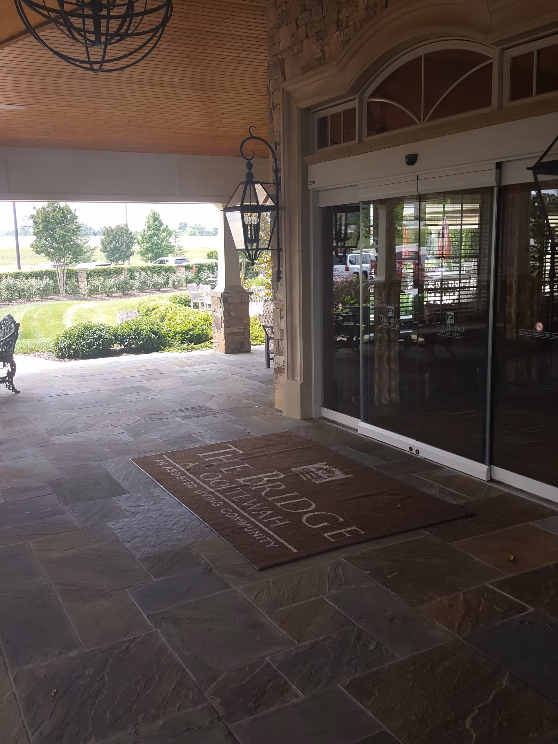 Front entrance of The Bridge at Ooltewah with stone facade, glass doors, and patio.