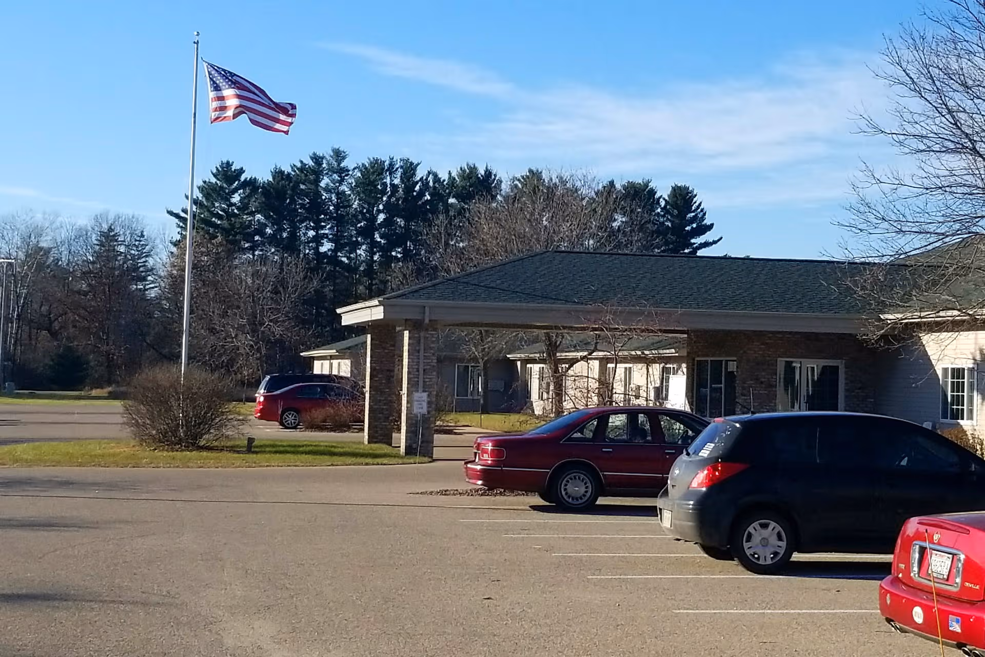 Exterior view of Heartland House with flagpole, parked cars, and a single-story building.