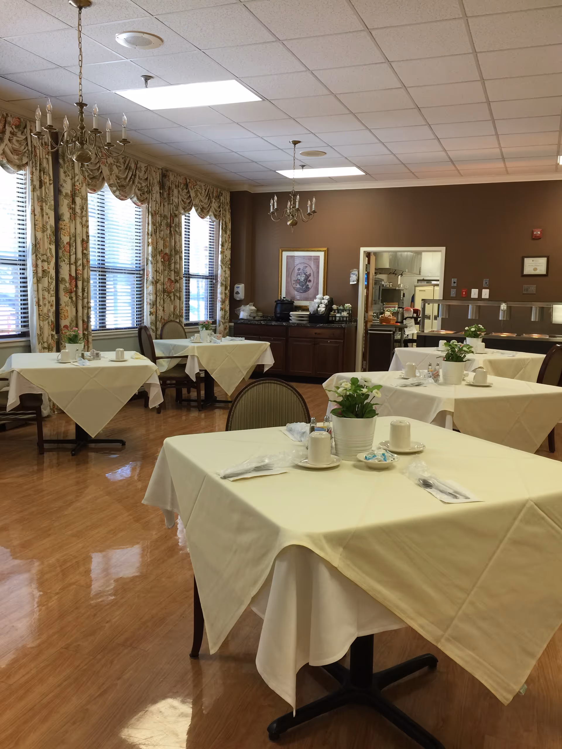 Dining room at Burke Health and Rehabilitation Center with tablecloths and plants.