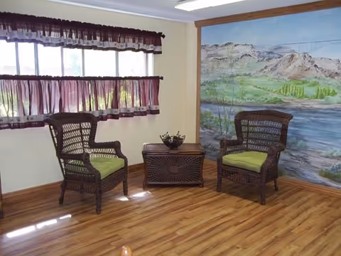 Two wicker chairs with lime cushions sit beside a small table and a mountain mural.
