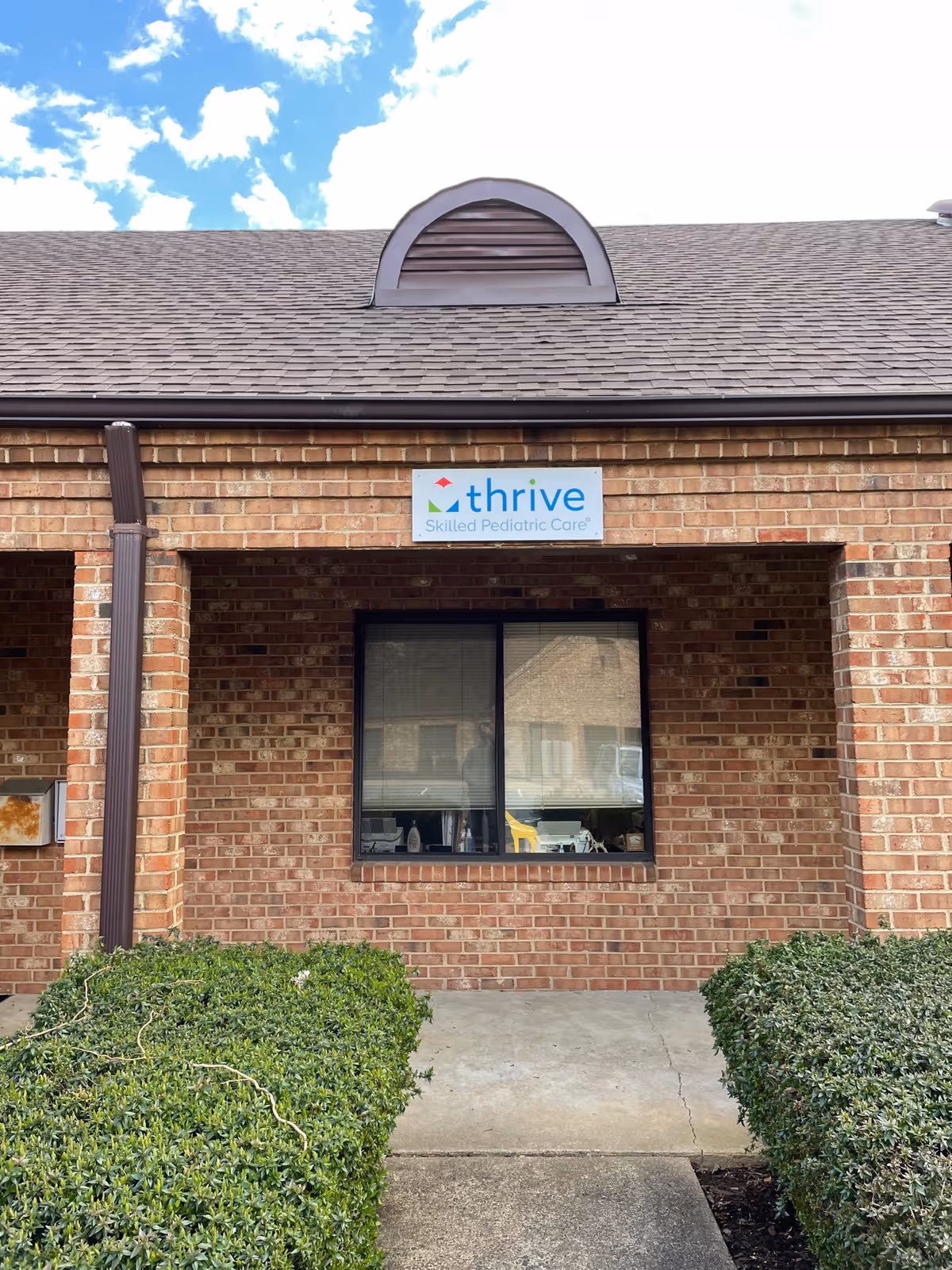 Brick facility exterior with Thrive sign above a window