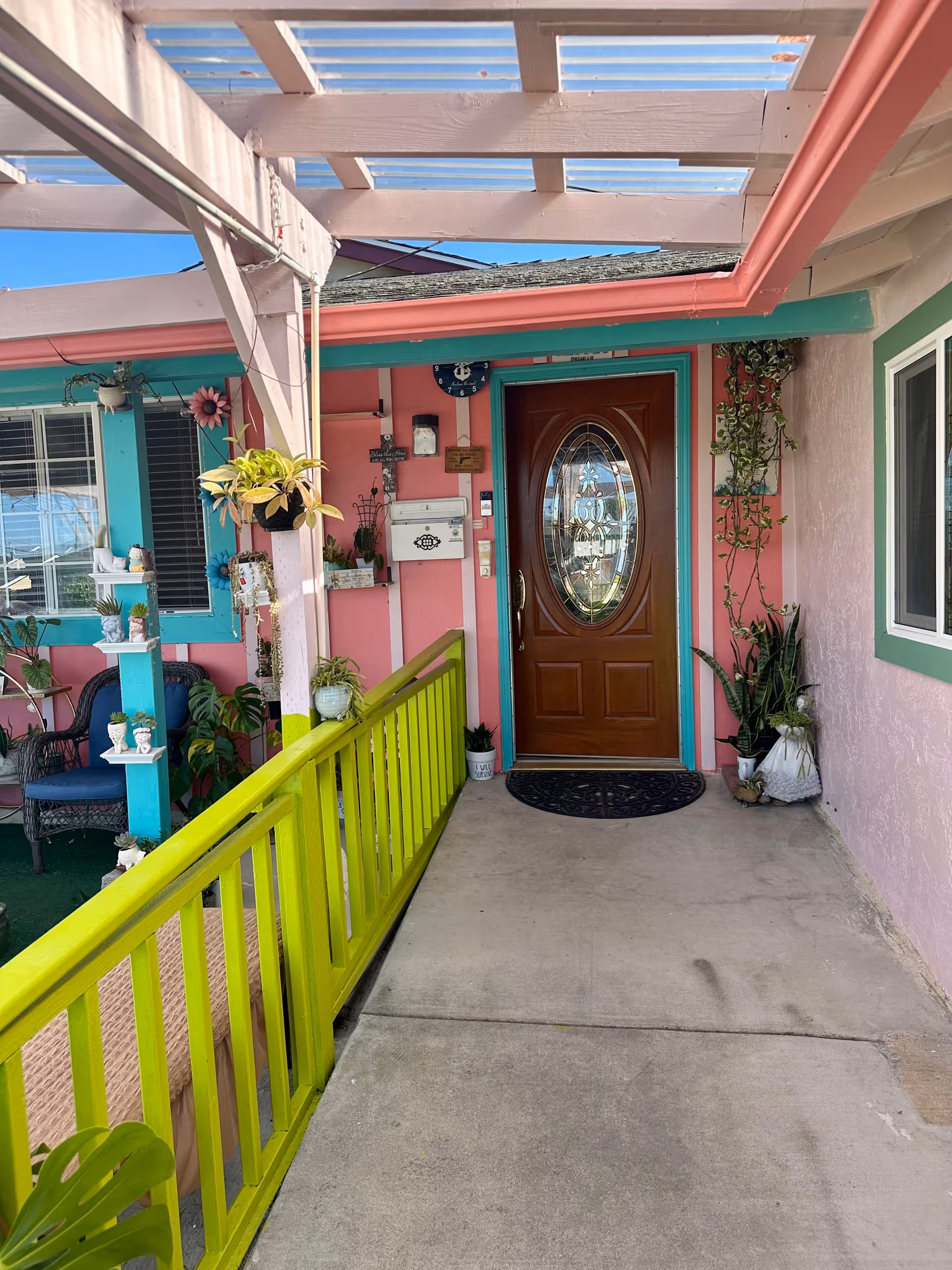 Colorful entryway to Anchor Elderly Care Home with bright pink walls and a wooden door.