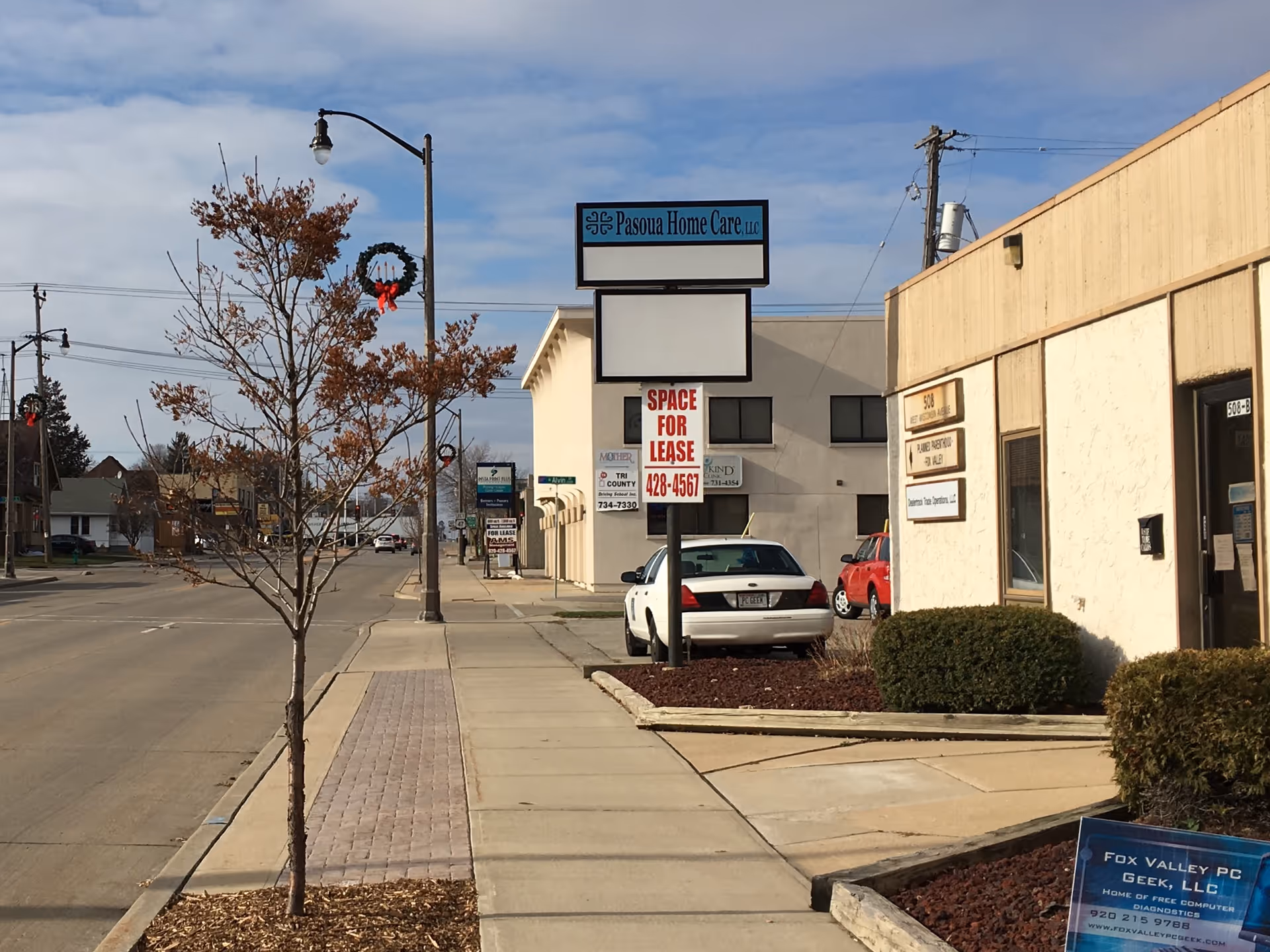 Street view of Pasoua Home Care LLC building with sign and parked cars