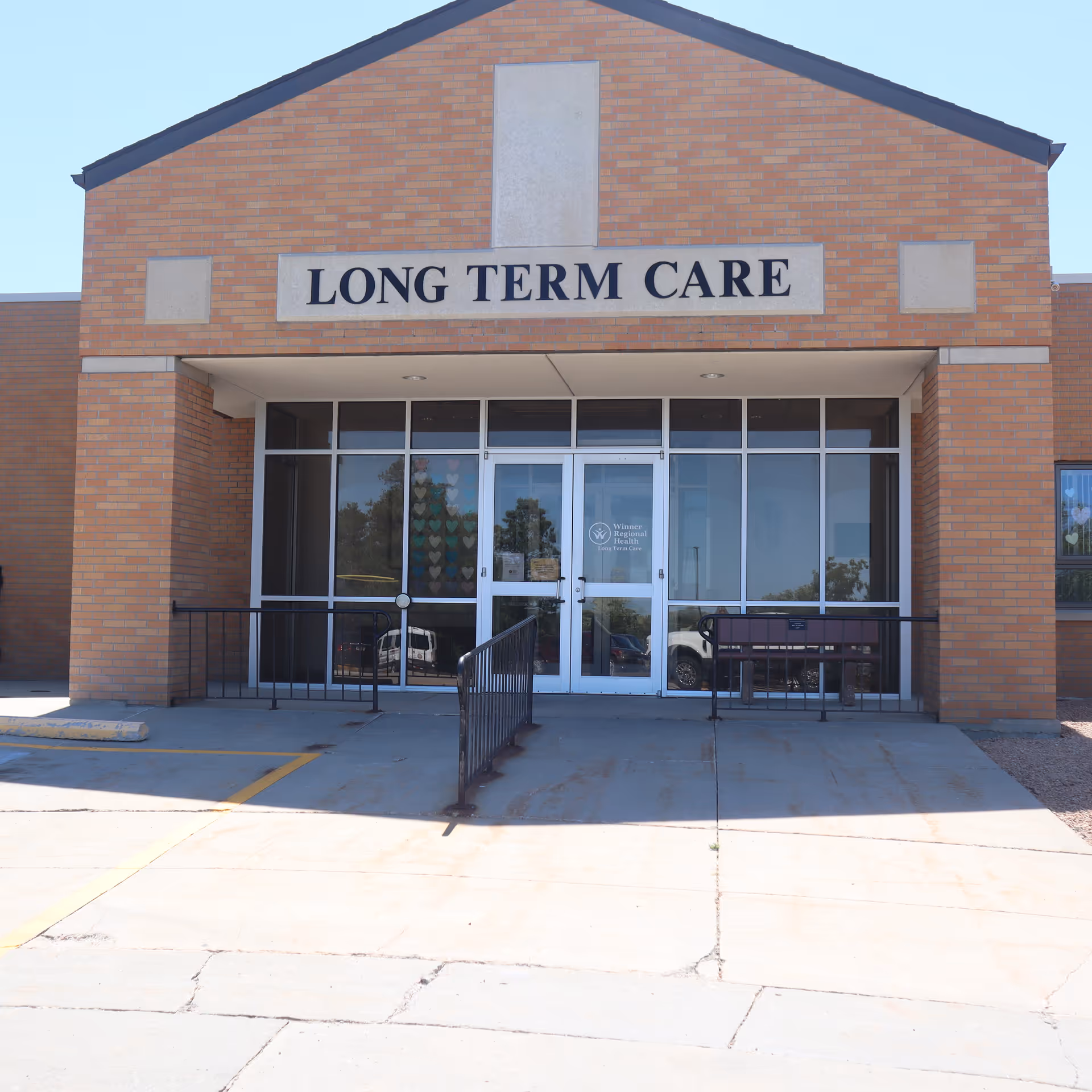 Brick building entrance with Long Term Care sign and glass doors.